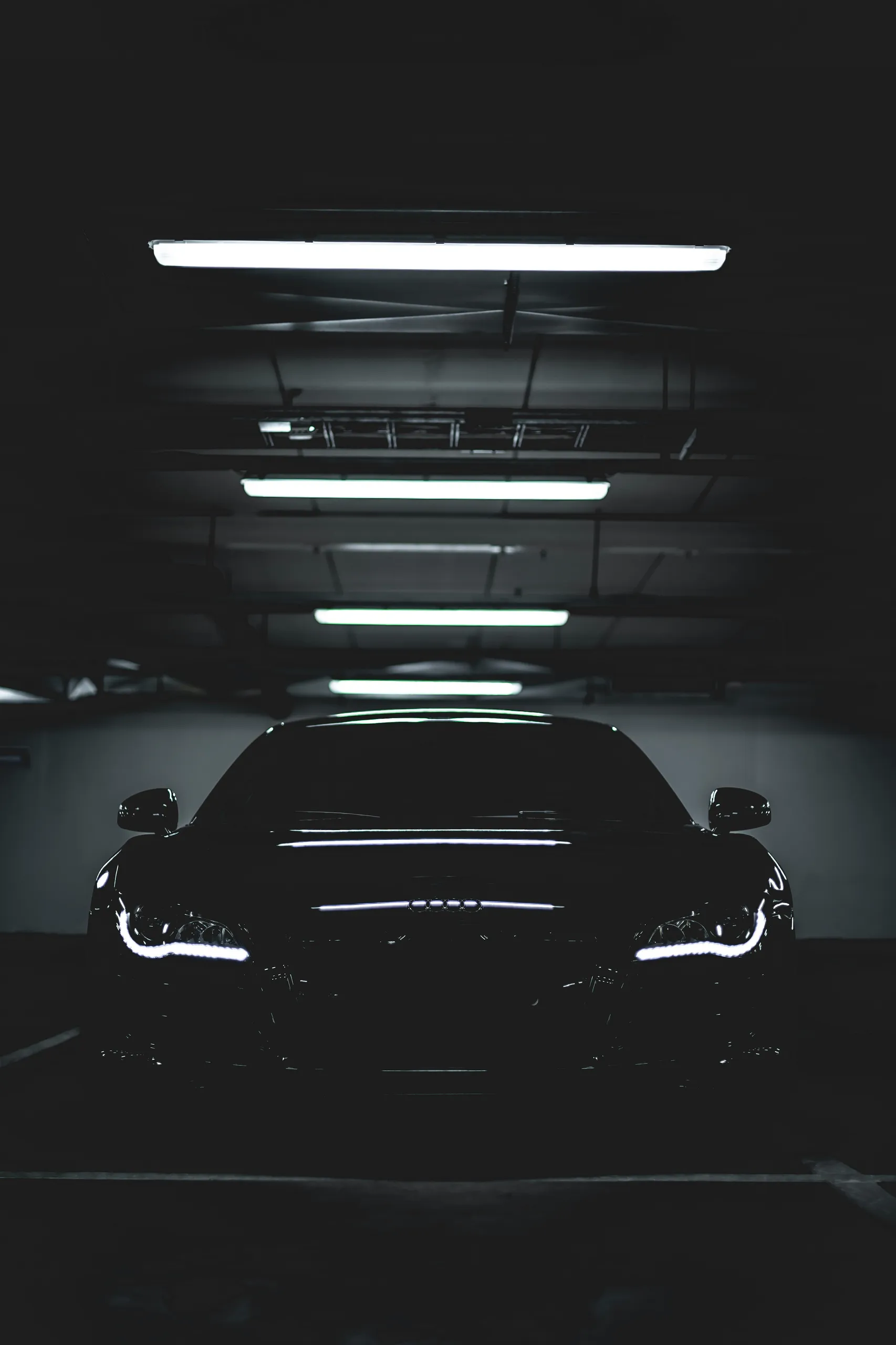 Czarne Audi R8 z głębokim lakierem w hali, mocne odbicia świateł